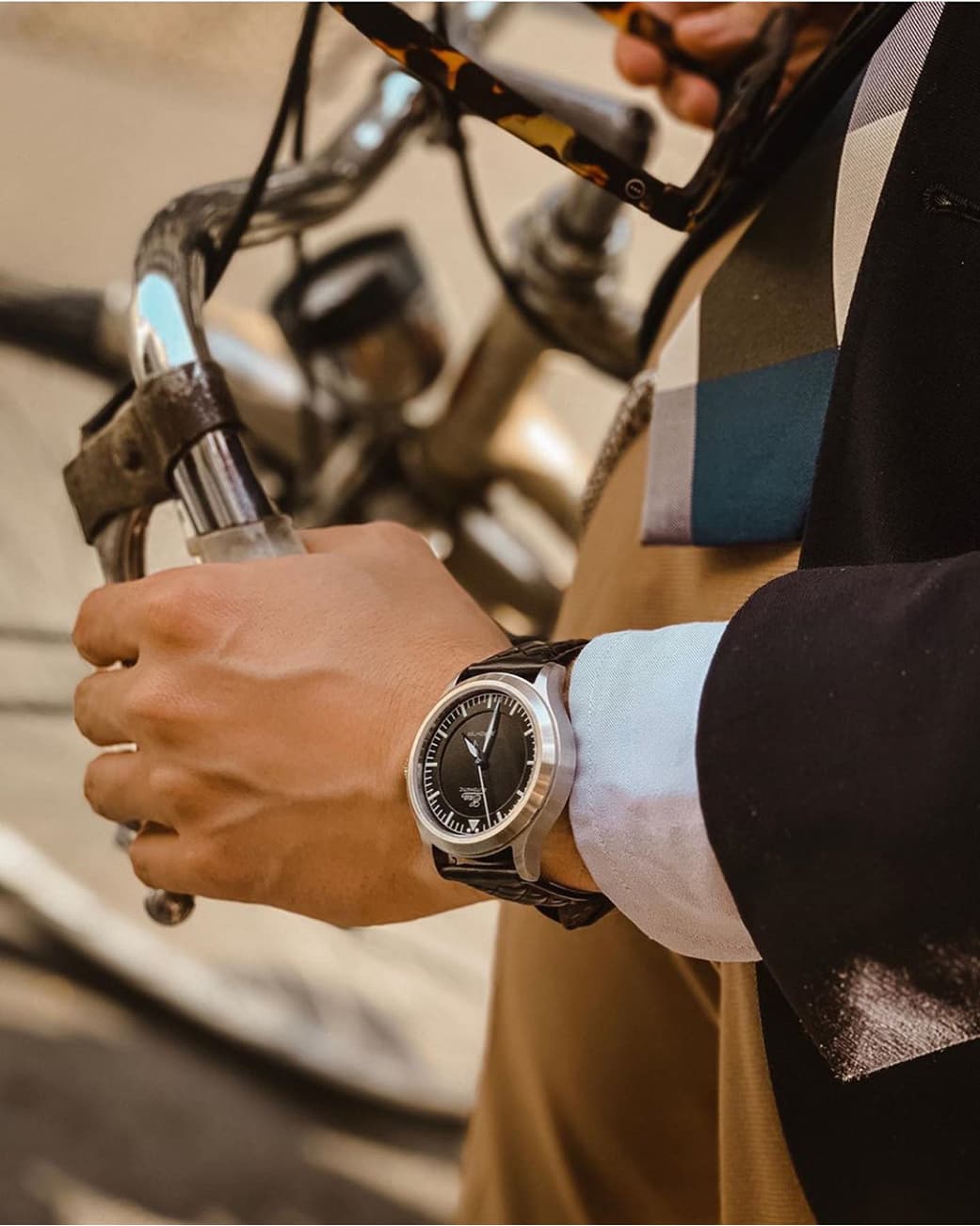 A person standing beside a bicycle while wearing a wristwatch